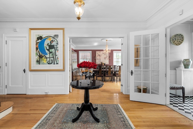 foyer with light hardwood / wood-style floors, an inviting chandelier, and ornamental molding