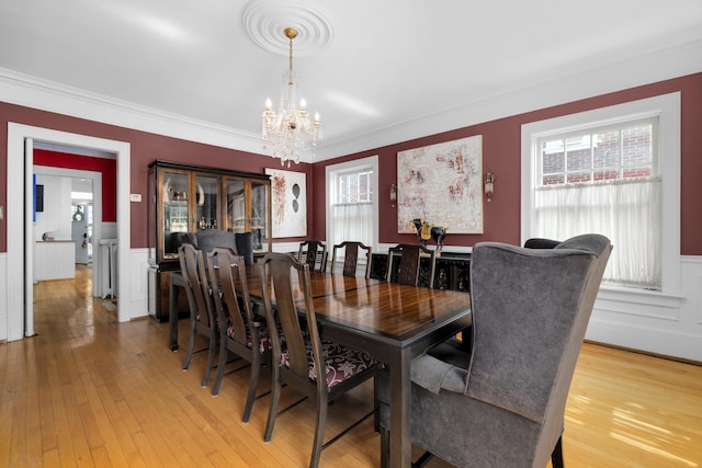 dining room with hardwood / wood-style floors, ornamental molding, and an inviting chandelier