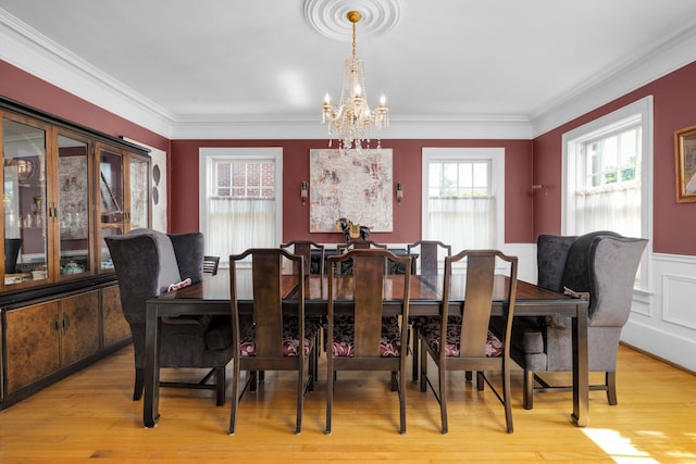 dining space with an inviting chandelier, ornamental molding, and light hardwood / wood-style flooring