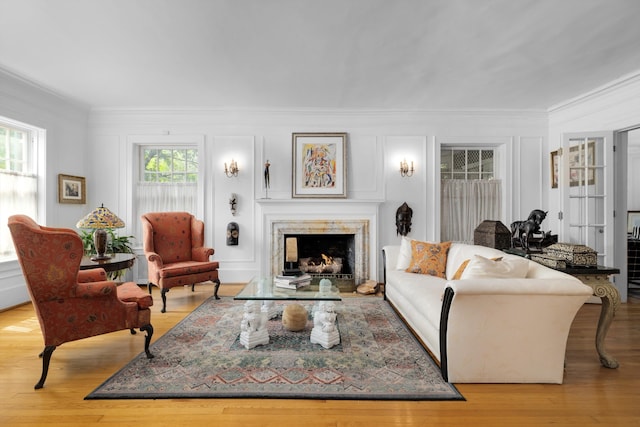 living room featuring ornamental molding, light hardwood / wood-style flooring, a healthy amount of sunlight, and a premium fireplace