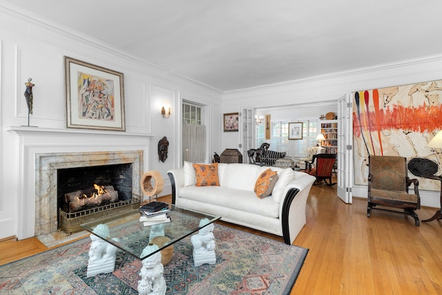 living room with light hardwood / wood-style floors, crown molding, and a fireplace