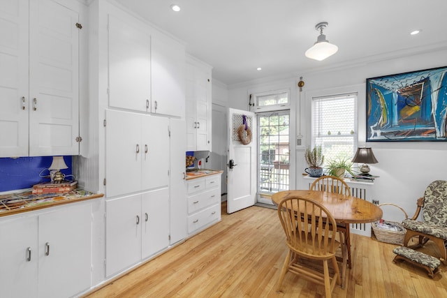 kitchen with white cabinets, light wood-type flooring, and backsplash