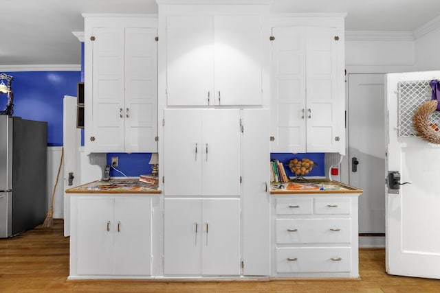 kitchen featuring white cabinetry, stainless steel refrigerator, crown molding, and light hardwood / wood-style floors