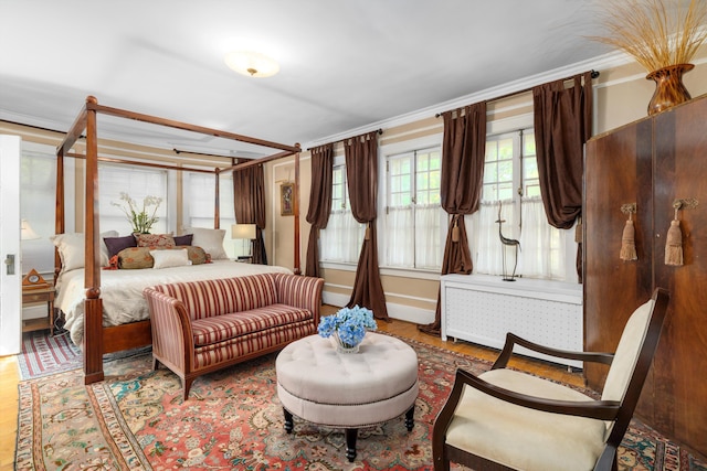 bedroom featuring radiator heating unit, light wood-type flooring, and crown molding