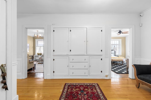 interior space with a chandelier, ornamental molding, a healthy amount of sunlight, and light hardwood / wood-style floors