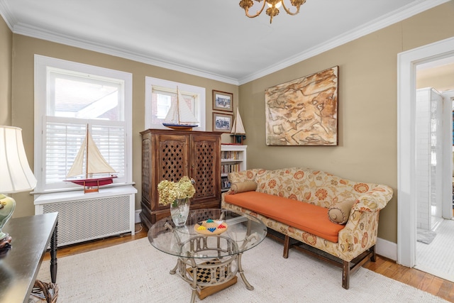 sitting room featuring radiator, a chandelier, wood-type flooring, and ornamental molding