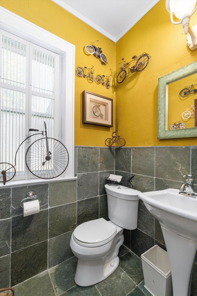 bathroom with tile patterned flooring, toilet, ornamental molding, and tile walls