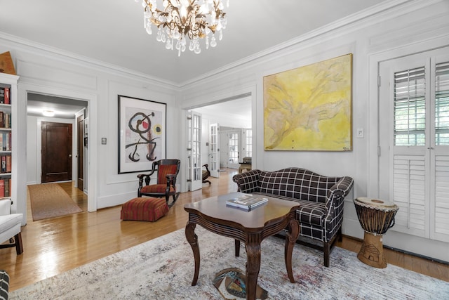 sitting room featuring hardwood / wood-style flooring, ornamental molding, and a chandelier