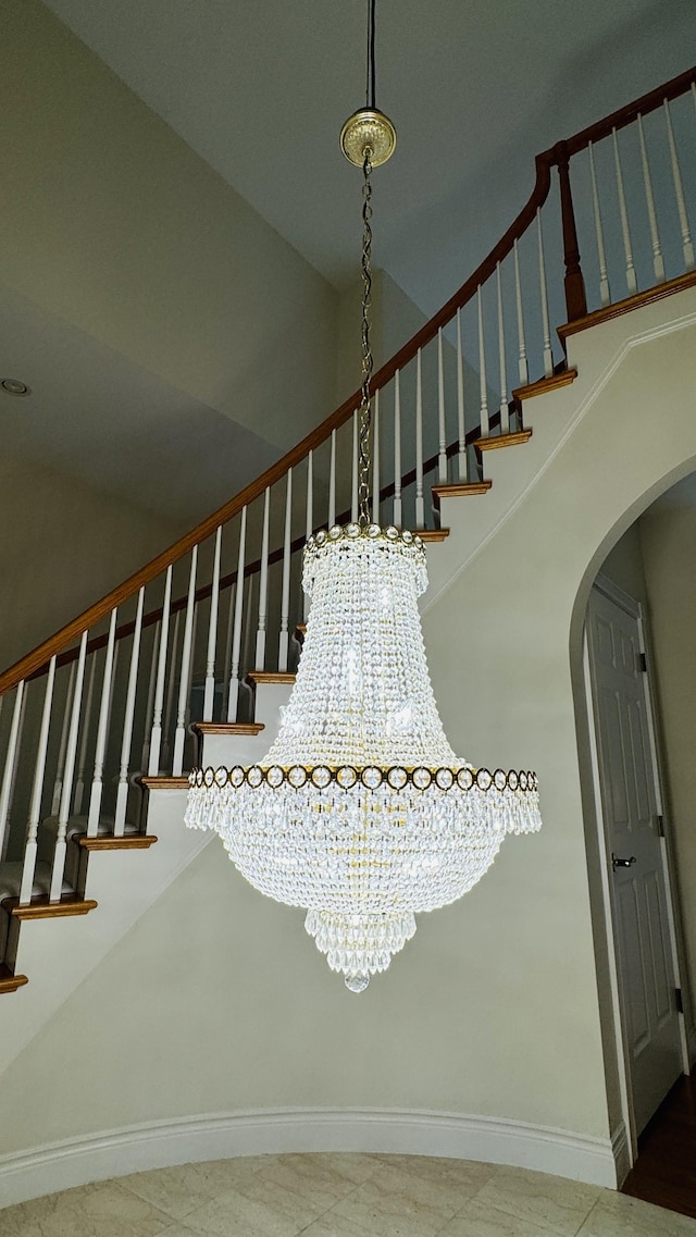 staircase with a towering ceiling and a chandelier