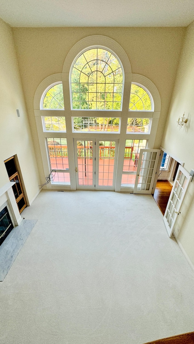 carpeted living room with french doors, plenty of natural light, and a high ceiling