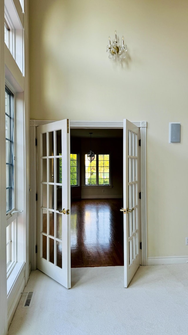 doorway to outside with french doors, carpet floors, and a notable chandelier