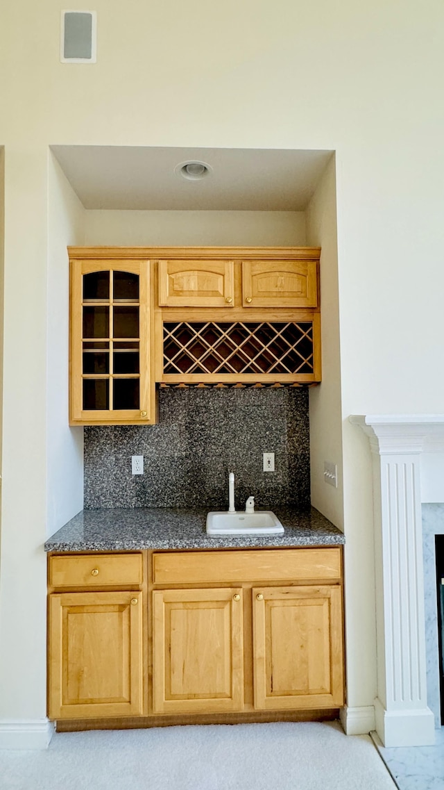 bar with decorative backsplash, dark stone countertops, and sink