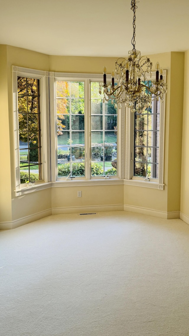 unfurnished dining area featuring a wealth of natural light, carpet, and a chandelier