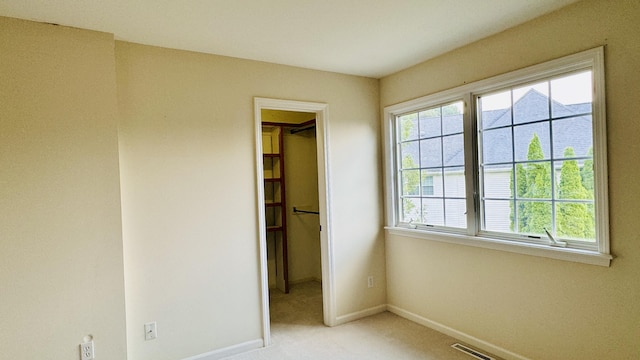 unfurnished bedroom featuring light colored carpet and a spacious closet