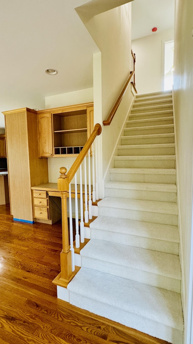 stairs featuring hardwood / wood-style floors and built in desk