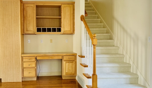 staircase featuring hardwood / wood-style floors and built in desk