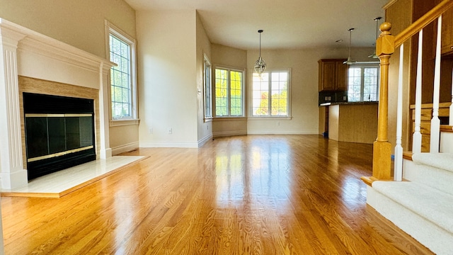 unfurnished living room featuring wood-type flooring, a wealth of natural light, and a notable chandelier