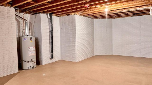 basement featuring water heater and brick wall