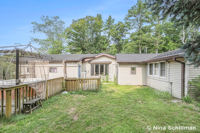 rear view of house featuring a lawn and a wooden deck