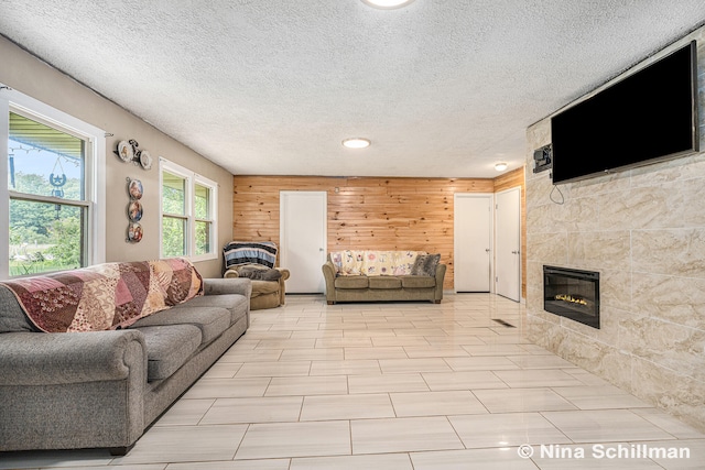 living room featuring a fireplace, a textured ceiling, and wooden walls