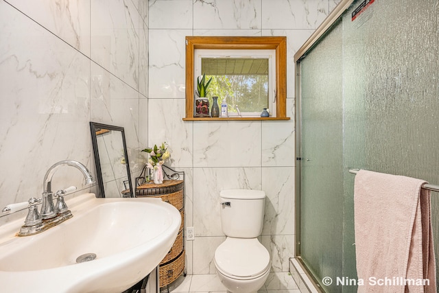 bathroom featuring tile patterned floors, sink, toilet, tile walls, and a shower with shower door