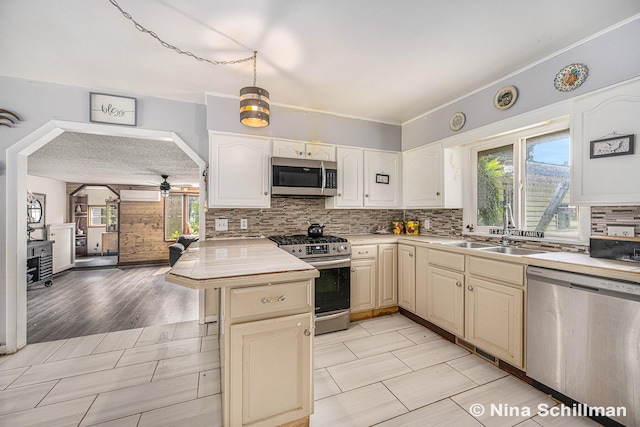 kitchen with ceiling fan, sink, stainless steel appliances, kitchen peninsula, and light wood-type flooring