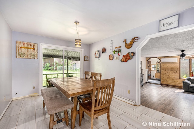 dining area featuring hardwood / wood-style floors, a wall unit AC, a wealth of natural light, and ceiling fan