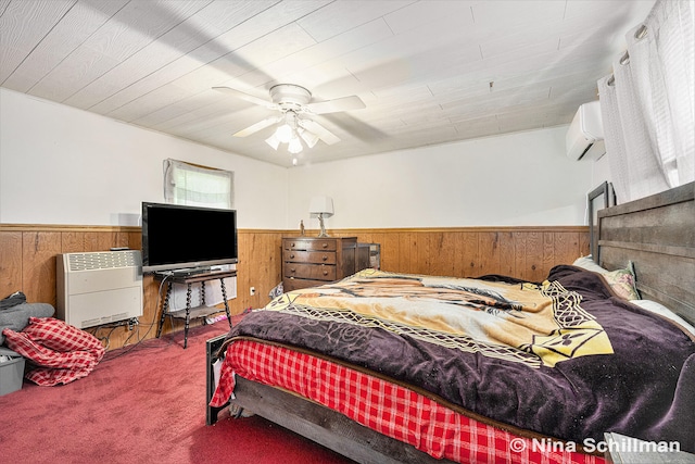 bedroom with heating unit, ceiling fan, carpet, and wood walls