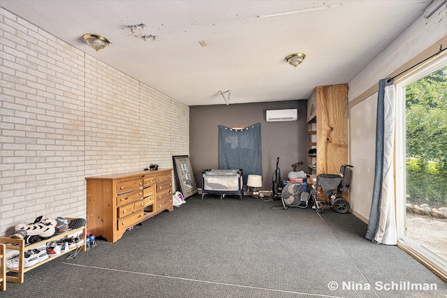 misc room featuring brick wall, a textured ceiling, and a wall unit AC