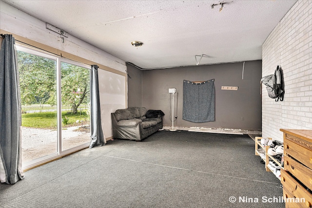 unfurnished room featuring carpet, a textured ceiling, and brick wall