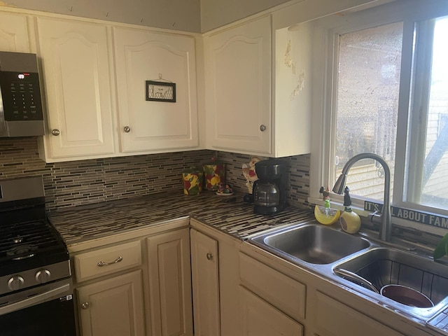 kitchen featuring tasteful backsplash, sink, white cabinets, and appliances with stainless steel finishes