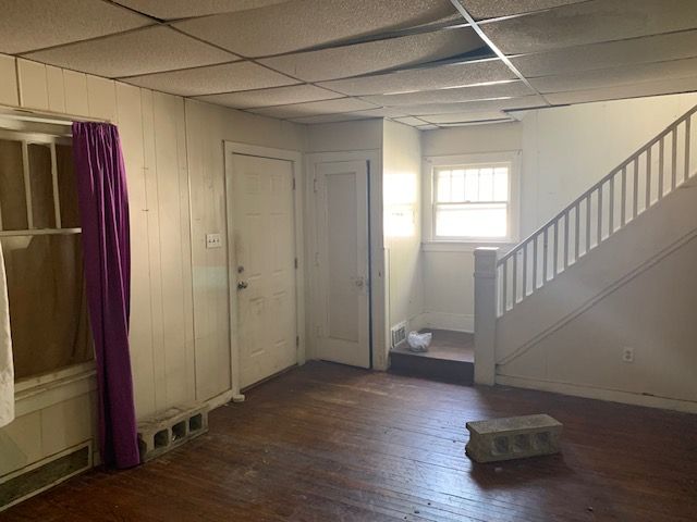 foyer featuring dark hardwood / wood-style floors, a drop ceiling, and wood walls