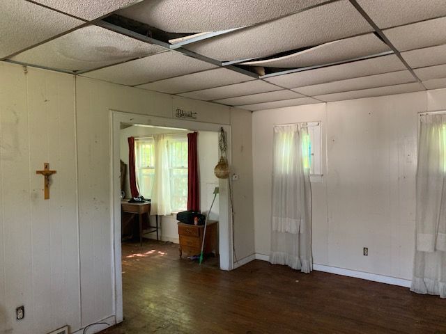 spare room featuring a paneled ceiling, dark hardwood / wood-style flooring, and a healthy amount of sunlight