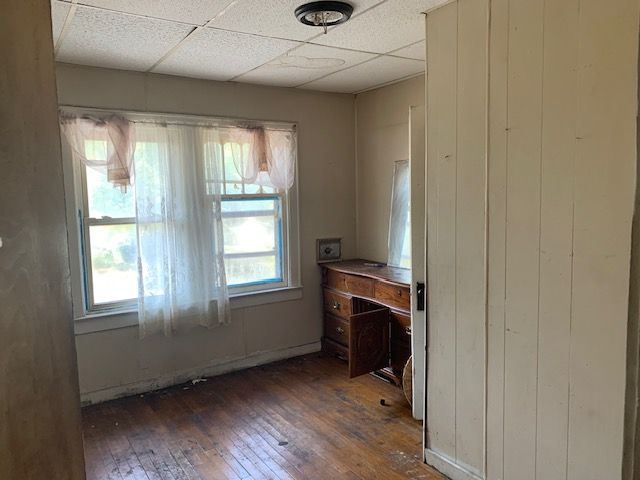 interior space featuring a paneled ceiling, dark hardwood / wood-style floors, and wood walls