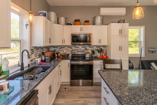 kitchen featuring white cabinets, stainless steel appliances, a wall mounted AC, and sink