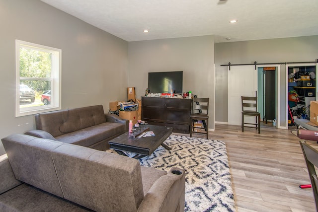 living room featuring a barn door and light hardwood / wood-style flooring