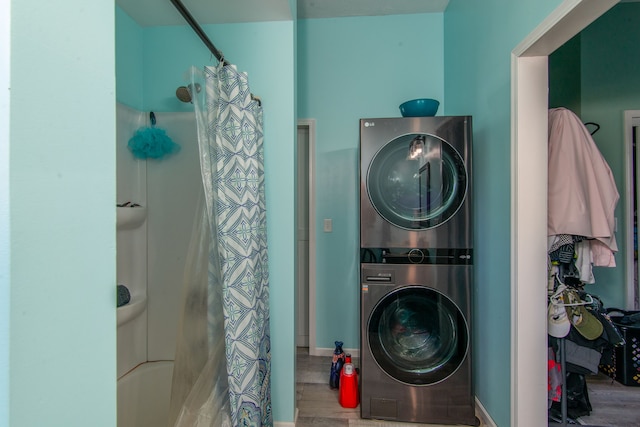 laundry room with hardwood / wood-style flooring and stacked washing maching and dryer