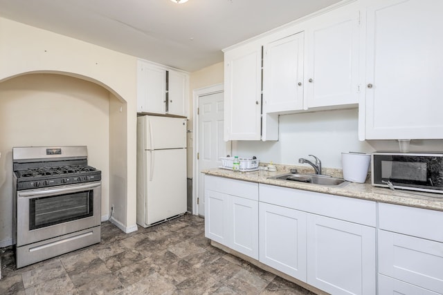 kitchen featuring white refrigerator, white cabinetry, sink, and stainless steel range with gas stovetop