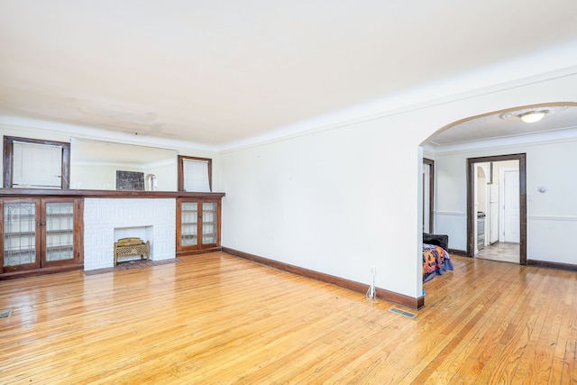 unfurnished living room with ornamental molding, a fireplace, and light hardwood / wood-style flooring