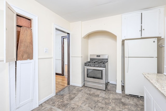 kitchen with white refrigerator, white cabinetry, and gas range