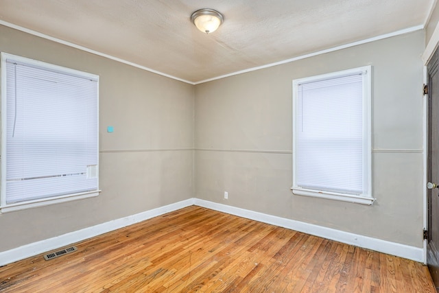 spare room with hardwood / wood-style flooring, ornamental molding, and a textured ceiling