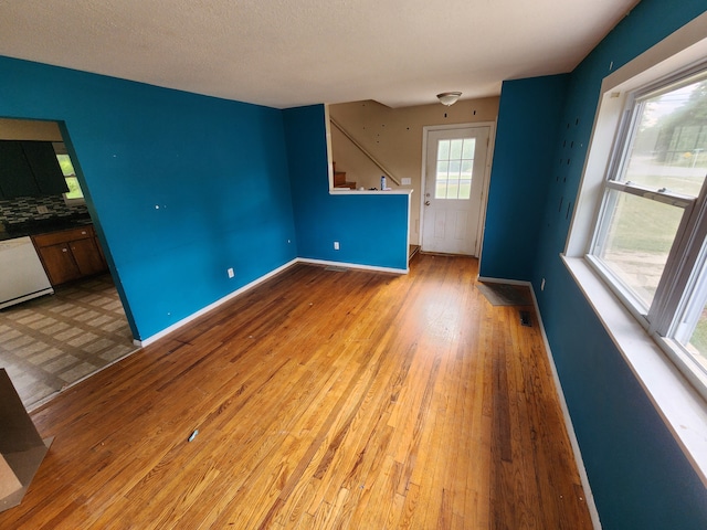 unfurnished living room featuring a textured ceiling and light hardwood / wood-style flooring