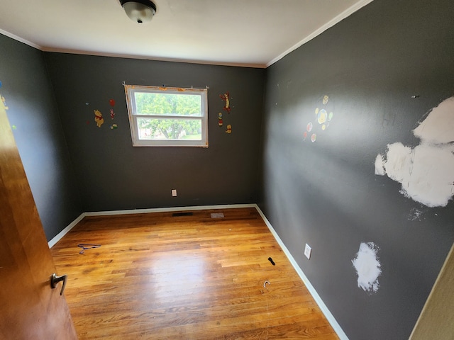 unfurnished room featuring wood-type flooring and crown molding