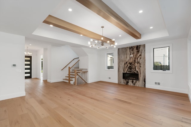 unfurnished living room with a fireplace, light hardwood / wood-style floors, and a chandelier