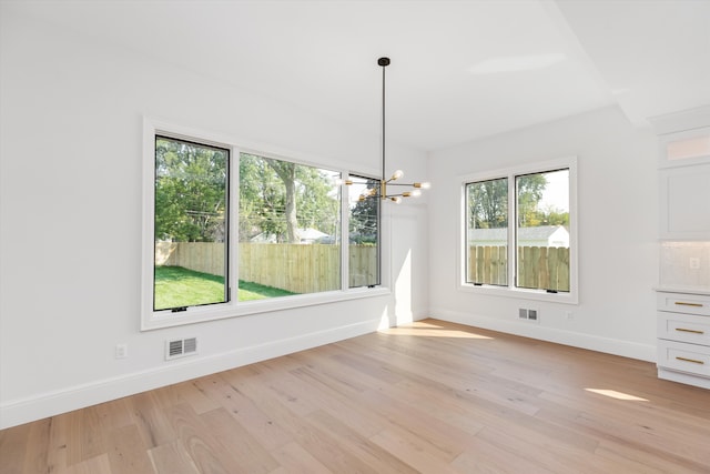 unfurnished dining area with light hardwood / wood-style floors and an inviting chandelier