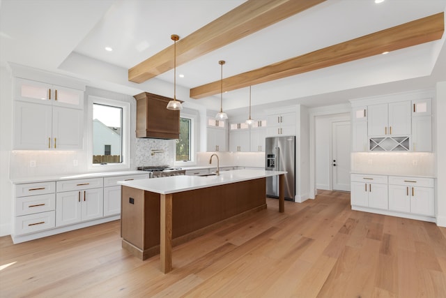 kitchen with beamed ceiling, tasteful backsplash, stainless steel appliances, and light hardwood / wood-style flooring