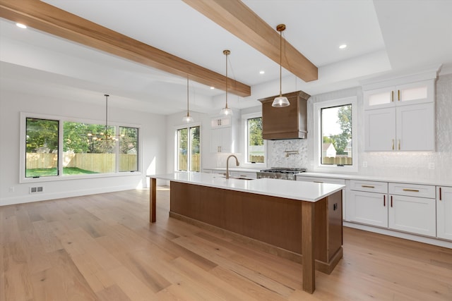 kitchen featuring white cabinets, beam ceiling, light hardwood / wood-style floors, and pendant lighting