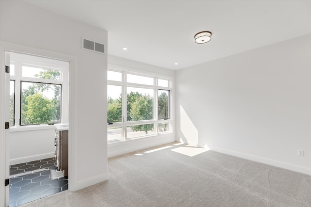 unfurnished room with plenty of natural light and dark carpet