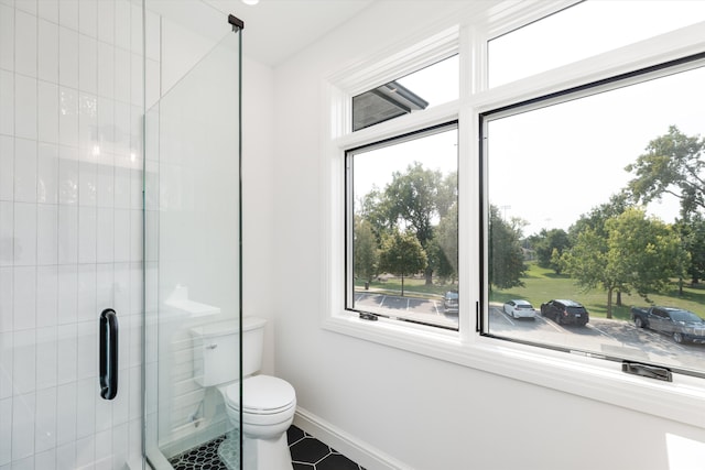 bathroom featuring tile patterned flooring, toilet, and a shower with door