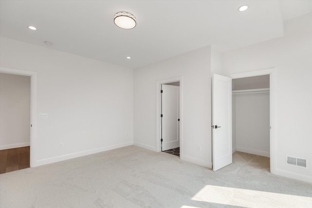 unfurnished bedroom with light carpet and a closet